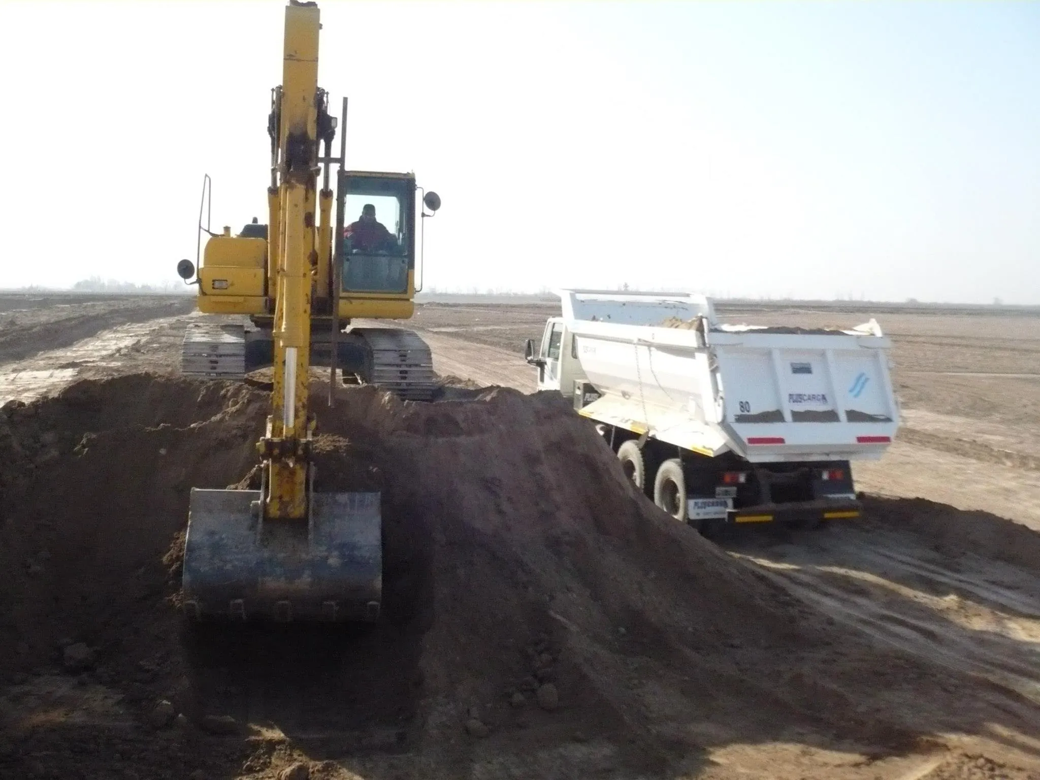 Excavadora sobre orugas cargando tierra en un camión volcador